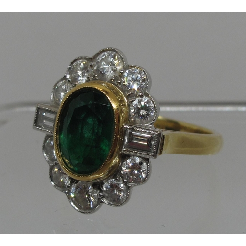 296 - A large emerald and diamond cluster ring.  The oval emerald approx 9x6mm surrounded by ten brilliant... 