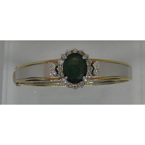 315 - Emerald and diamond hinged bangle set in yellow and white 18ct gold.  The treated emerald approx 14x... 