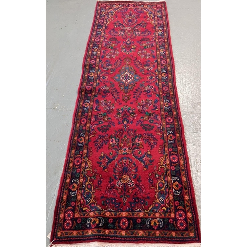 429 - Large thick pile Persian runner on a red ground with floral and foliate design.  330x106cm approx.  ... 