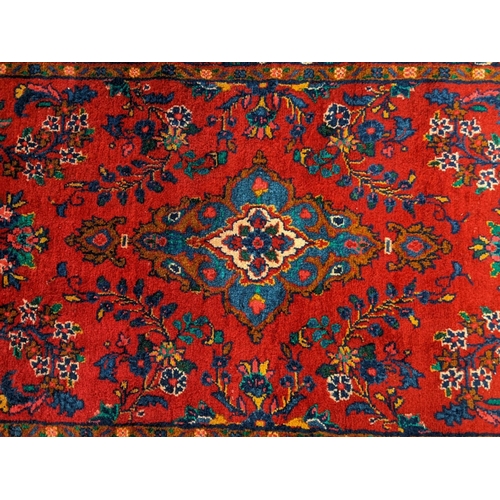 429 - Large thick pile Persian runner on a red ground with floral and foliate design.  330x106cm approx.  ... 