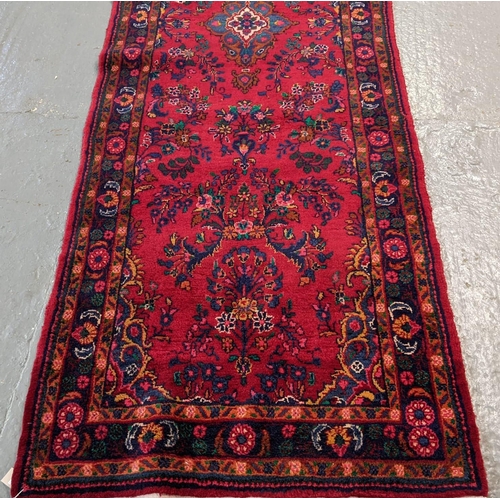 429 - Large thick pile Persian runner on a red ground with floral and foliate design.  330x106cm approx.  ... 