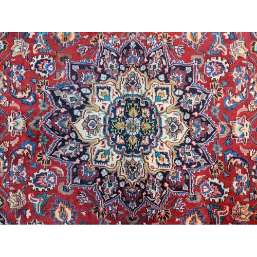 436 - Red ground Persian Mashad carpet having floral medallion to the centre.  300x197cm approx.   (B.P. 2... 