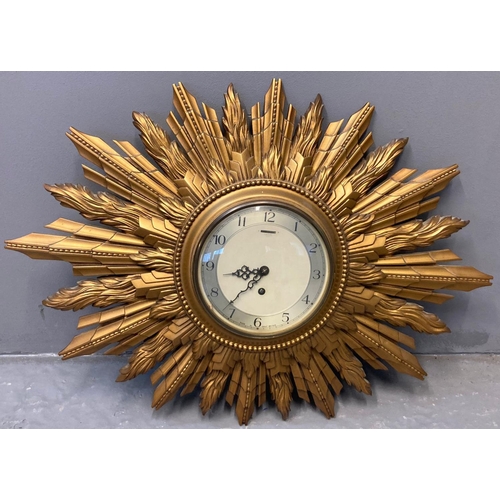 72 - Early 20th century Smiths eight day gilded sunburst clock with Arabic face. With key.  Overall 67cm ... 