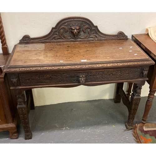 558 - Late Victorian ornately carved oak side table, the gallery back with moulded mask head mount, having... 