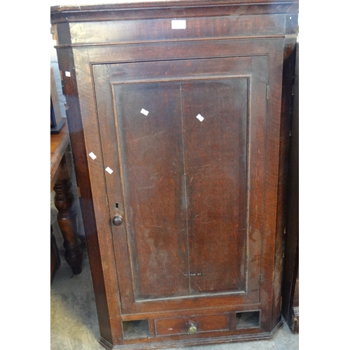 537 - Early 19th oak hanging corner cupboard with blind panelled door revealing shaped shelves to the inte... 