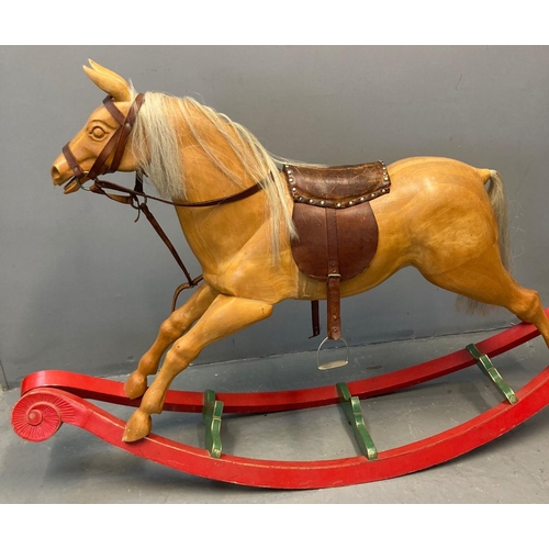 34 - Vintage child's carved rocking horse with leather reigns, saddle and stirrups on a red and green pai... 