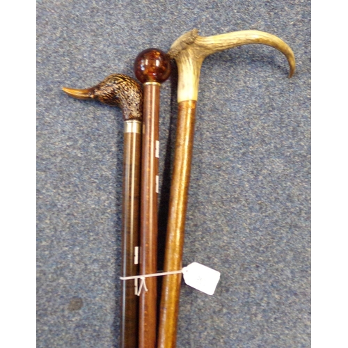 201 - Three walking sticks to include: duck's head, antler and simulated amber knops.  (3)   (B.P. 21% + V... 