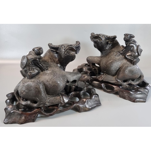 27 - Pair of Japanese carved hardwood studies of Water Buffalo with children on their backs, having pierc... 