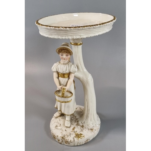 3 - Royal Worcester figure of a girl in the Kate Greenaway style, holding a basket and standing under a ... 