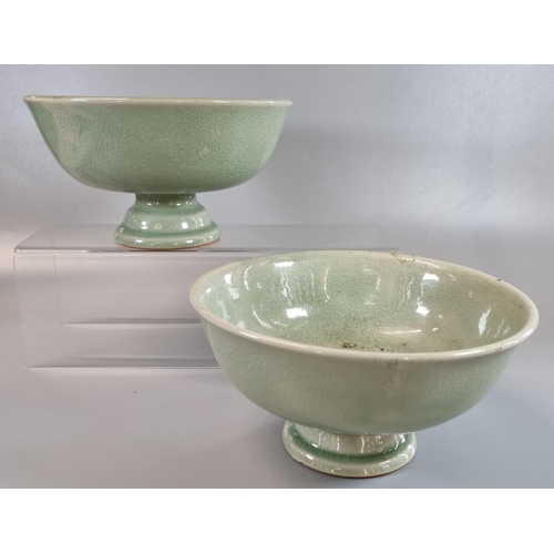 61 - A pair of oriental celadon glazed heavily potted porcelain stem bowls. Impressed marks to bases but ... 