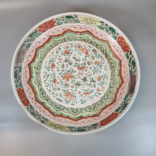 17th/18th century Chinese porcelain Wucai design Famille Verte polychrome decorated porcelain dish, overall with central rondel of flowers and foliage surrounded by green Ruyi heads on a yellow ground, green and iron red foliate bands and iron red daiper , outer band of red, yellow and aubergine flower heads.  Overall interspersed with panels of green enamel scrolling on an iron red cell ground.  Reverse decorated with four iron red and green enamel floral sprigs with a red and green petal diaper around the channelled foot.  Kangxi period. 36cm diameter approx.  (B.P. 21% + VAT)