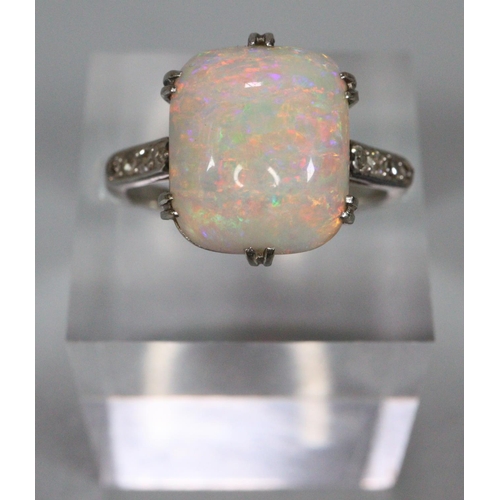 Opal ring with diamond shoulders, the cushion shaped opal 12x10mm approx, set in platinum.   Size N.  5.7g approx.  (B.P. 21% + VAT)