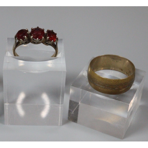 208 - 9ct gold three stone garnet dress ring and a gold plated wedding ring.  (2)  (B.P. 21% + VAT)