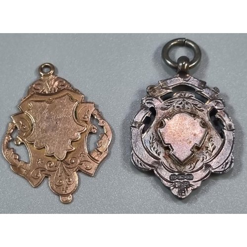 213 - Engraved silver shield shaped fob together with another similar in 9ct gold.  (2)  (B.P. 21% + VAT)