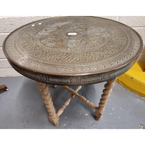 434 - Indian brass topped table on folding barley-twist turned wooden base.   (B.P. 21% + VAT)