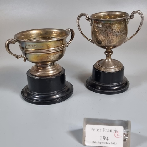 194 - Two small silver two handled trophy cups, both on ebonised bases (one fixed).  (B.P. 21% + VAT)