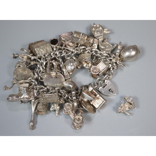 219 - Silver charm bracelet with a large collection of assorted charms. 4 troy ozs approx. 
(B.P. 21% + VA... 