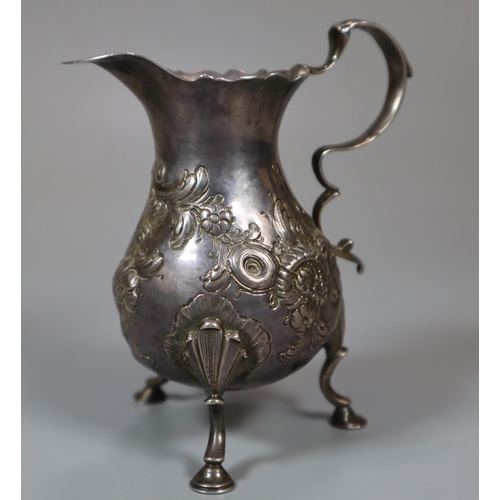 225 - Georgian silver repoussé floral and foliate cream jug standing on three hoof feet.  London hallmarks... 