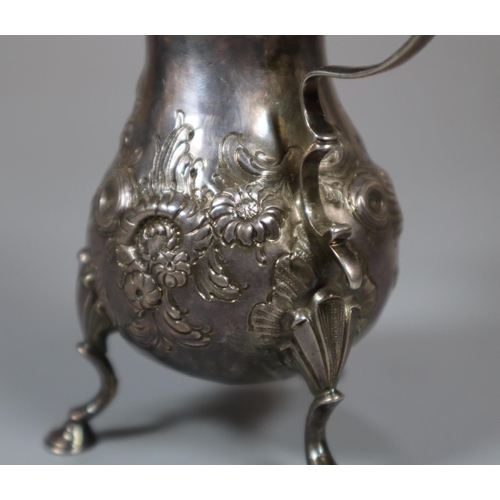 225 - Georgian silver repoussé floral and foliate cream jug standing on three hoof feet.  London hallmarks... 