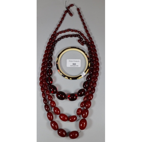 302 - Three 1930s cherry Bakelite graduated necklaces.  164g approx.  together with a Japanese design bang... 