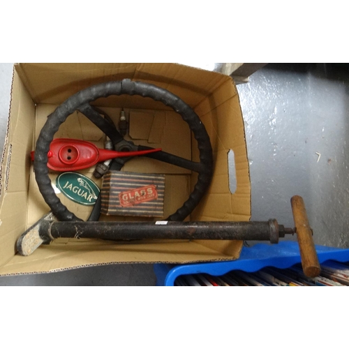 411 - Box of automobilia to include: tyre jack, steering wheel, oil can, Jaguar sticker, side lamp in orig... 