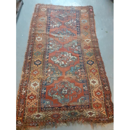 535 - Kurdish rug on a red ground decorated with stylised geometric panels and medallions.  225x120cm appr... 