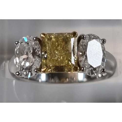 335 - 18ct white gold fancy grade three stone diamond ring, the central stone drawing yellow colour, two b... 