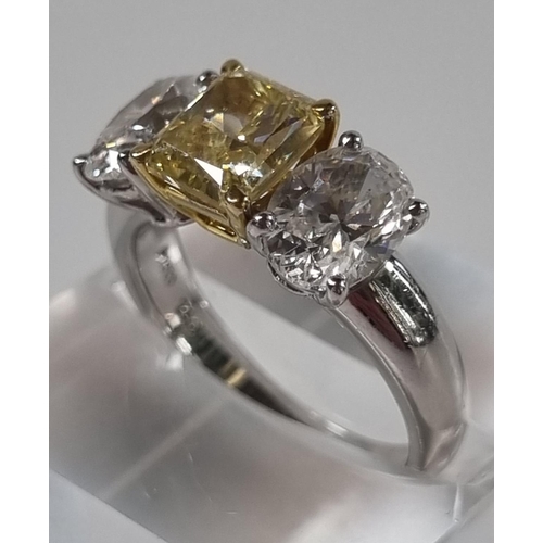 335 - 18ct white gold fancy grade three stone diamond ring, the central stone drawing yellow colour, two b... 