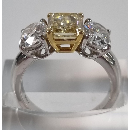 335 - 18ct white gold fancy grade three stone diamond ring, the central stone drawing yellow colour, two b... 