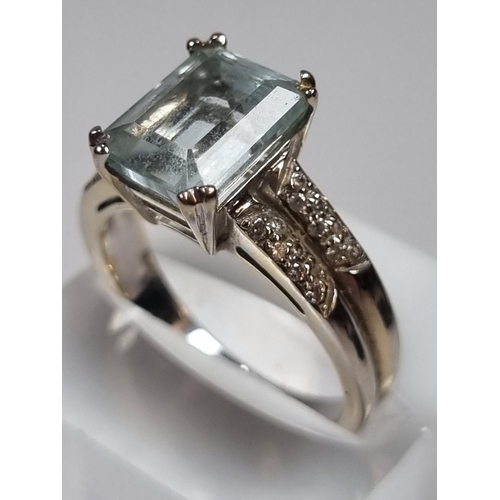 345 - White metal aquamarine and diamond ring, the central stone flanked by an arrangement of small diamon... 