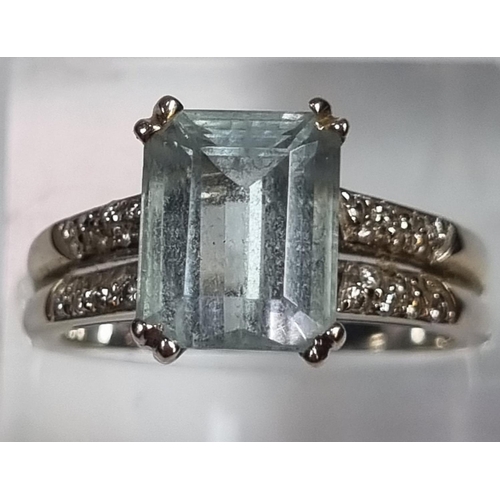 345 - White metal aquamarine and diamond ring, the central stone flanked by an arrangement of small diamon... 