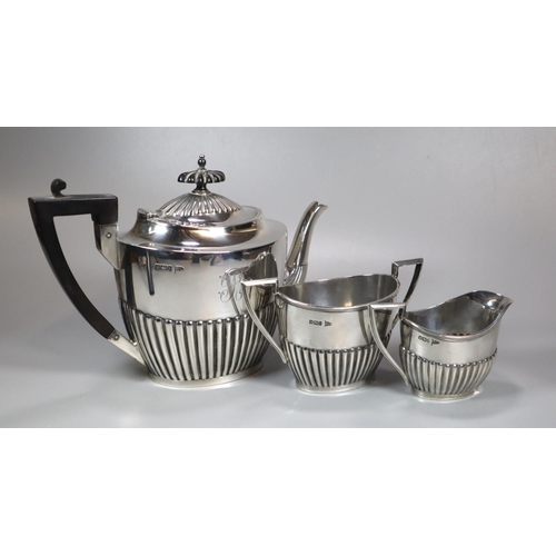 443 - Edward VII silver fluted three piece service, the teapot with geometric ebonised handle, to include:... 