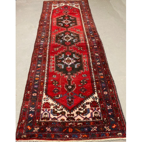 471 - Red and blue ground Iranian runner with traditional medallion designs and repeating floral borders. ... 