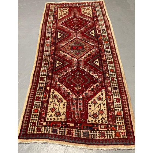 472 - Cream and red ground Persian Mishkin runner with repeating central medallion designs and repeating g... 