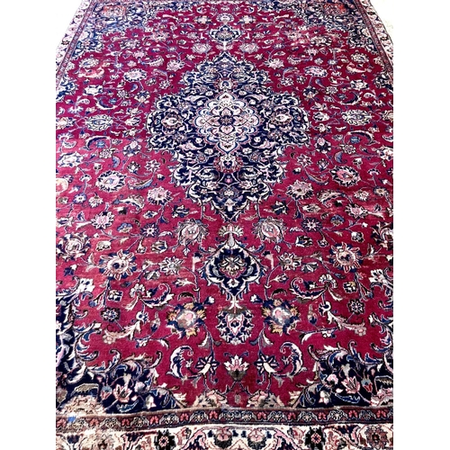 476 - Rich red ground Persian Mashad carpet with traditional floral medallion designs.  305x223cm approx. ... 