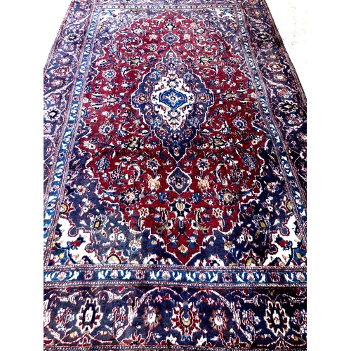 477 - Red and blue ground Persian Kashan carpet with traditional floral designs.  285x176cm approx.  (B.P.... 