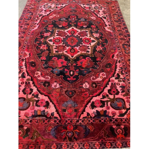 478 - Full wool pile hand woven Persian carpet on a pink and red ground with large central medallion and r... 