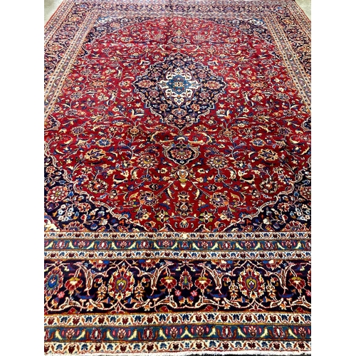 479 - Large fine hand woven Iranian carpet on a red and navy ground with large central medallion.  Kashan ... 