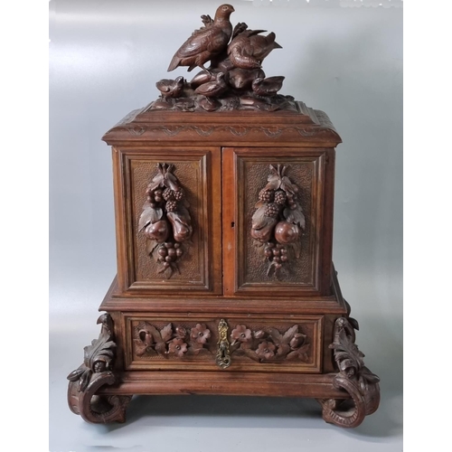 Late 19th century Black Forest walnut Humidor, the top carved with partridge and young above two doors with moulded fruits and leaves, the interior revealing a bank of four drawers above another drawer with relief flowers and foliage on ornately carved feet.  58x23x43cm approx.  (B.P. 21% + VAT)