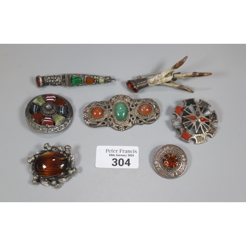 304 - Plastic box of Scottish Agate and stone brooches, together with a Scottish claw brooch.  (B.P. 21% +... 