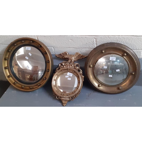 411 - Two gilt framed convex mirrors, together with another modern gilded convex mirror with eagle pedimen... 