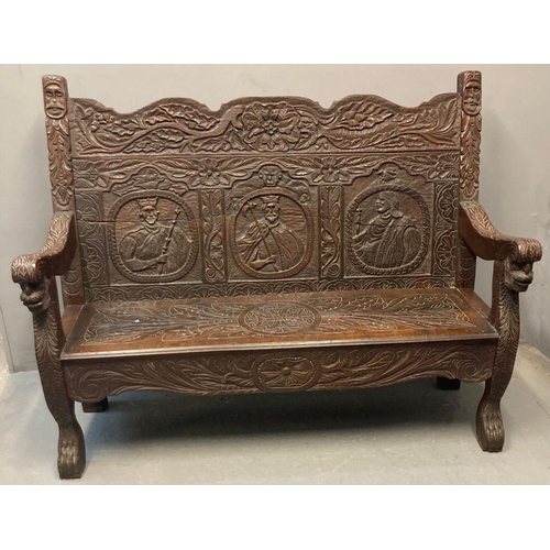 488 - 19th century oak Flemish style settle, the shaped back with carved decoration of mask heads and thre... 