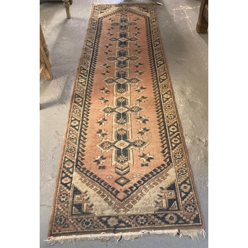 565 - Salmon ground Middle Eastern design runner with repeating lozenge and floral designs.  272x77cm appr... 