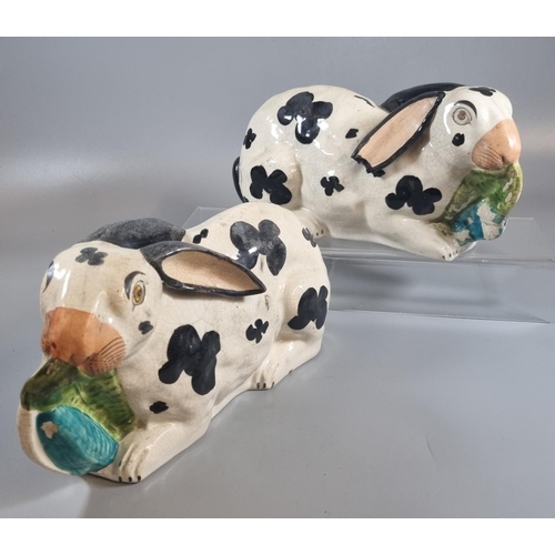 2 - Pair of 19th century Staffordshire Pottery black and white recumbent Rabbits with leaves in their mo...