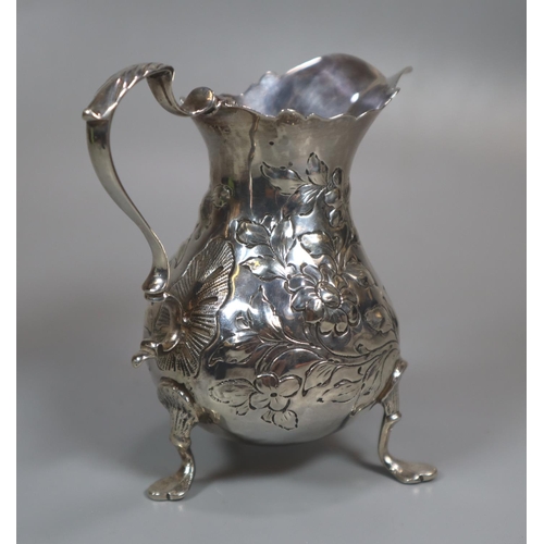 303 - 19th century silver helmet shaped cream jug decorated with repoussé flowers and foliage on three sha... 