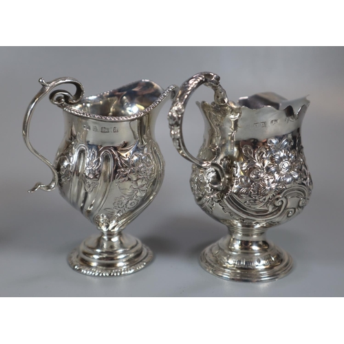 313 - Two similar silver repoussé helmet shaped cream jugs together with a similar silver sauce boat.  12.... 