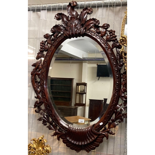 489 - Modern hardwood bevelled mirror of oval form, the frame decorated with flowers, fruits and foliage. ... 