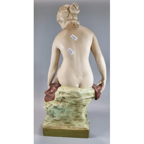 132 - Early 20th century Royal Dux figure of a seated nude female bather, modelled on a rocky outcrop.  48... 