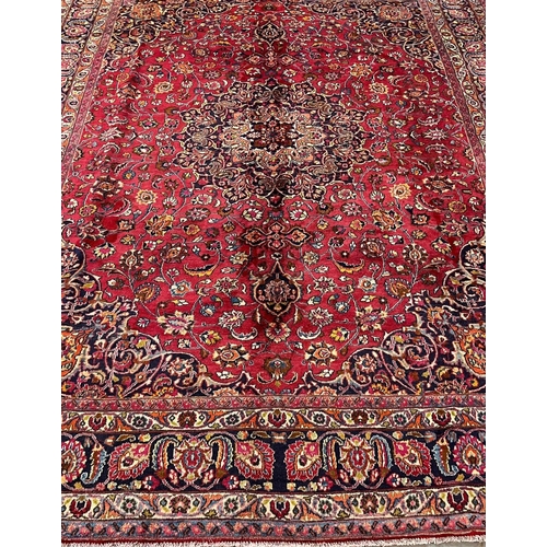 302 - Large red ground Persian Mashad carpet, overall on a red ground with floral and foliate designs, cen... 