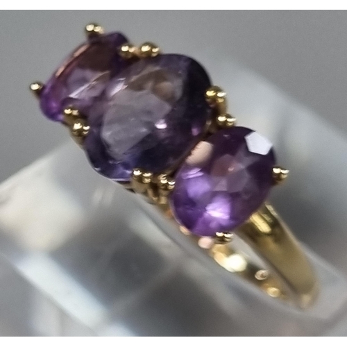 215 - 9ct gold and purple three stone dress ring.  2.7g approx. Size P.   (B.P. 21% + VAT)